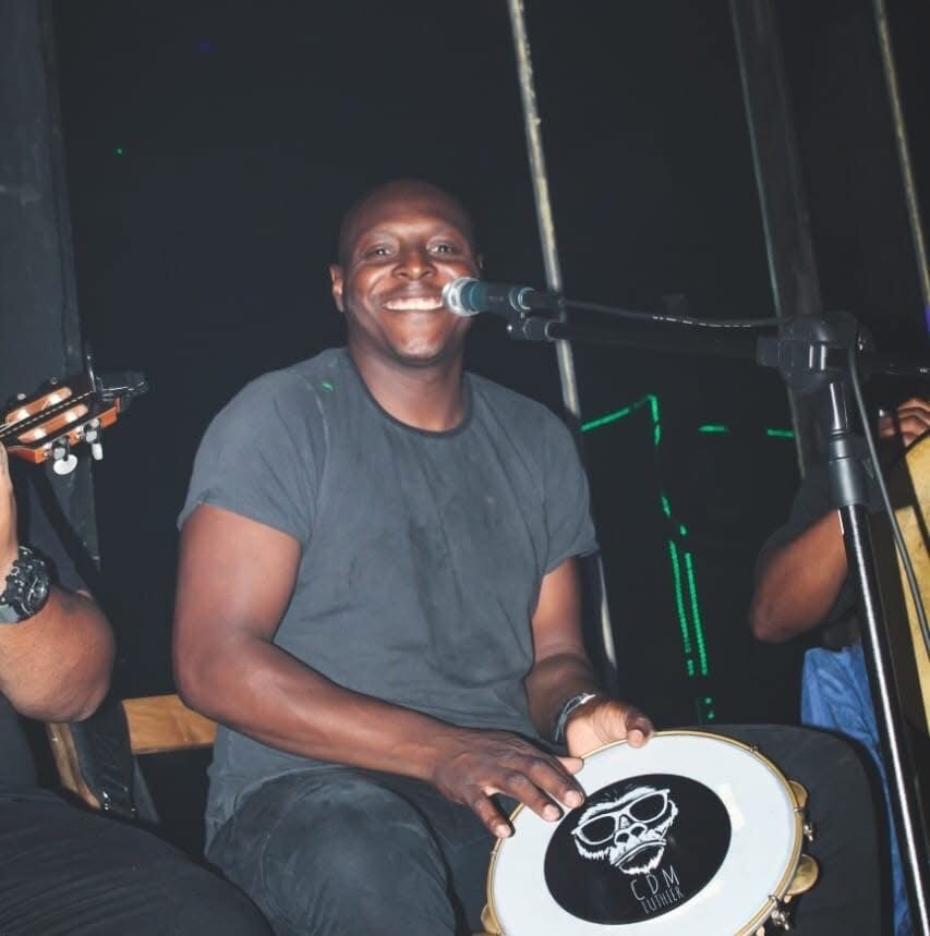 Sambista sorrindo com pandeiro durante roda íntima